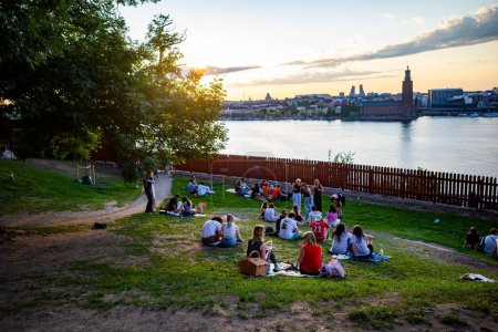 Foto de Estocolmo, Suecia 24 de junio de 2023 Personas sentadas en la hierba al atardecer en pleno verano en el emblemático Ivar Lo Park en Sodermalm. - Imagen libre de derechos