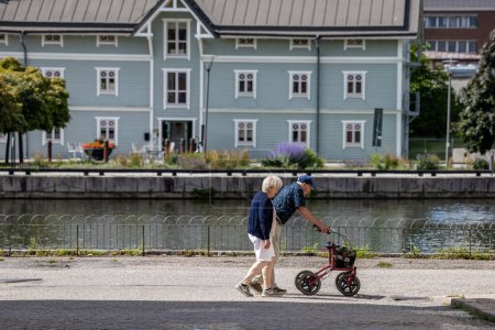 Téléchargez les photos : Eskilstuna, Suède 22 juillet 2023 Un couple âgé marche avec une poussette le long de la rivière Eskilstuna. - en image libre de droit