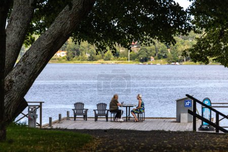Téléchargez les photos : Sundbyholm, Suède 22 juillet 2023 Deux femmes s'assoient à une table dans le parc du château de Sundbyholm en été sur le lac Malaren. - en image libre de droit