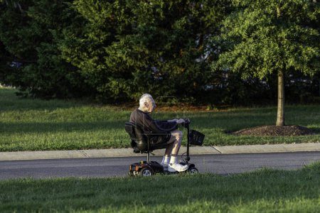 Photo for Solomons, Maryland, USA A senior retired man rides an electric battery-driven mobility scooter in a park. - Royalty Free Image