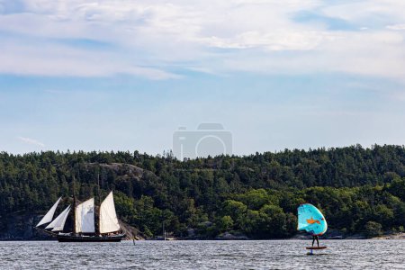 Photo for Stockholm, Sweden Sept 8, 2023 A gaff schooner sailing vessel and a man on a wingfoil in the Baltic Sea outside the capital. - Royalty Free Image