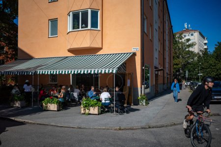 Téléchargez les photos : Stockholm, Suède 17 Sept, 2023 Les gens assis dans un café en plein air dans le quartier Aspudden sur Manhemsplatsen - en image libre de droit