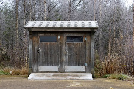 Photo for Torvinen, Finland A small public wooden outhouse in a parking lot. - Royalty Free Image
