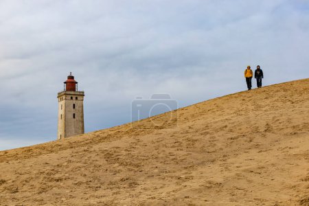 Téléchargez les photos : Le phare de Rubjerg Knude, Danemark Nov 1, 2023 Une vue du célèbre phare de Rubjerg Knude qui a été déplacé en raison de l'érosion des dunes et de l'eau en 2018, et des personnes marchant. - en image libre de droit