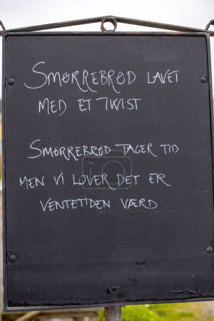 Photo for Lonstrup, Denmark Nov 1, 2023 A menu outside a restaurant says in Danish, "Smorrebrod with a twist. Smorrebrod takes time to make but it is worth the wait. " - Royalty Free Image