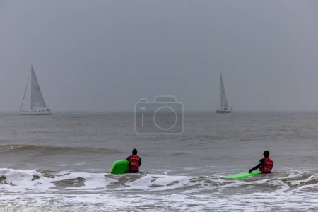 Foto de La Haya, Países Bajos Nov 12, 2023 Surfistas en el agua con trajes de neopreno en la playa de Scheveningen. - Imagen libre de derechos