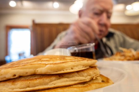 Photo for Prince Frederick, Maryland USA A senior man eats breakfast at a pancake restaurant. - Royalty Free Image
