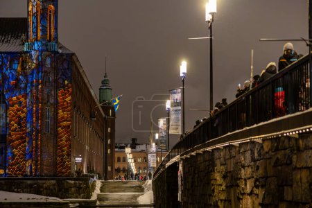 Téléchargez les photos : Stockholm, Suède Dec 9, 2023 Les gens regardent un spectacle de lumière sur la façade de l'hôtel de ville de Stockholm ou Stadshuset pour célébrer la Semaine Nobel de la Lumière. - en image libre de droit
