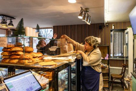 Téléchargez les photos : Stockholm, Suède Une serveuse dans un café remet une commande de repas à un service de livraison. - en image libre de droit