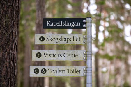 Photo for Stockholm, Sweden Dec 31, 2023 Directional signs in Swedish and English in the Woodlawn Cemetery, or Skogskyrkogarden, a Unesco World Heritage site, in winter, for chapel, toilets and visitors center. - Royalty Free Image