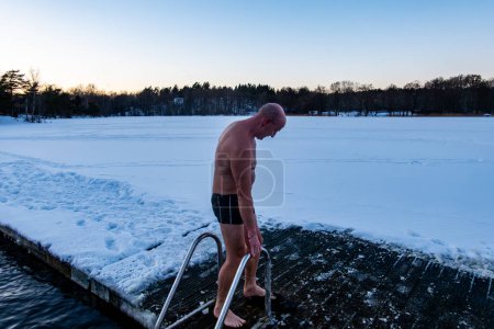 Téléchargez les photos : Stockholm, Suède Un homme se baignant sur la glace d'un quai dans un lac gelé. - en image libre de droit
