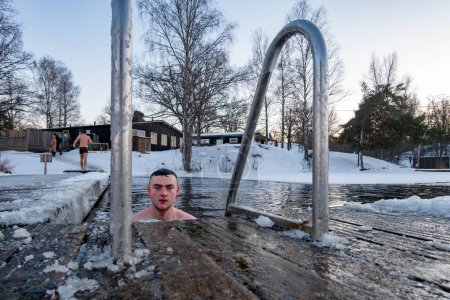 Téléchargez les photos : Stockholm, Suède Un jeune homme se baignant sur la glace d'un quai dans un lac gelé. - en image libre de droit