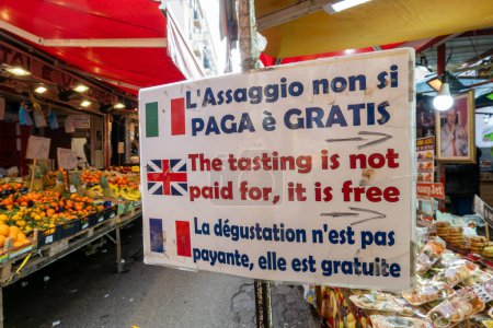 Foto de Palermo, Sicilia, Italia Ene 12, 2024 Un cartel en el mercado callejero Mercato di Ballaro en italiano Francés e Inglés dice: La degustación no está pagada, es gratis." - Imagen libre de derechos