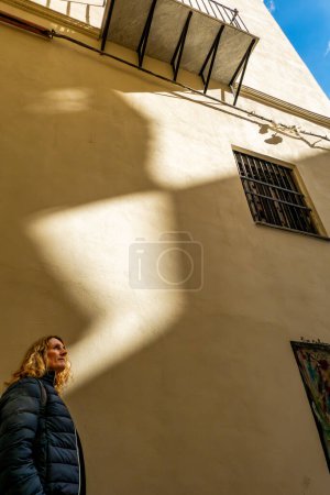 Palermo, Sicily, Italy A tourist woman stands againsta a yellow wall in the histroical center as a ray of light falls onto the wall.
