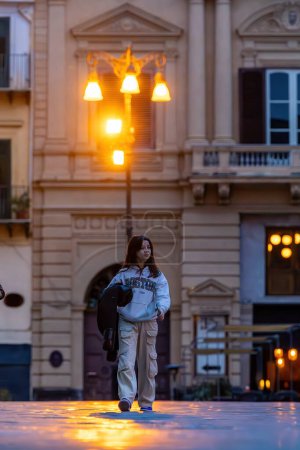 Foto de Palermo, Sicilia, Italia Jan 19, 2024 Una joven caminando por la noche en Piazza Bellini en el centro histórico. - Imagen libre de derechos