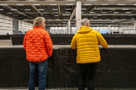 Téléchargez les photos : Stockholm, Suède Jan 26, 2024 Deux hommes en vestes aux couleurs vives visitent un salon de la moto et se présentent à un test. piste. - en image libre de droit