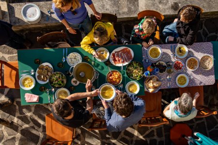 Photo for Goriano, Sicoli, Italy feb 19, 2024 A group of friends with children having dinner outside on the patio. - Royalty Free Image