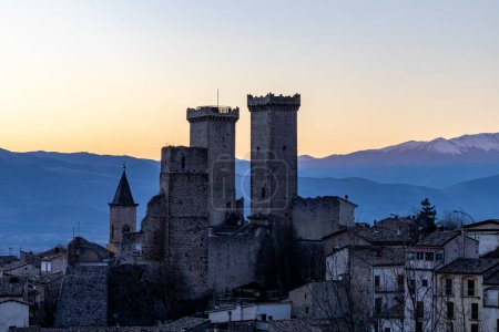 Pacentro, Italien Die Skyline der Stadt bei Sonnenuntergang mit den Burgtürmen und der Kirche, das Schloss Cantelmo-Caldora.