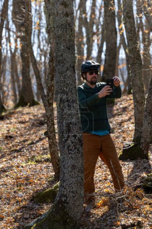 Goriano Sicoli, Italie Un homme photographie un peuplement de jeunes chênes dans une forêt par une journée ensoleillée avec un appareil photo mobile.