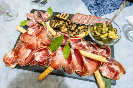 Goriano, Sicoli, Italy A plate of antipasto on a table with hams, salami, proscuitto, zuchinni, and eggplant.