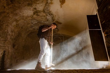 Roccamorice, Italy A man sweeps a dirt floor Eremo di San Bartolomeo sanctuary, an old monastery.