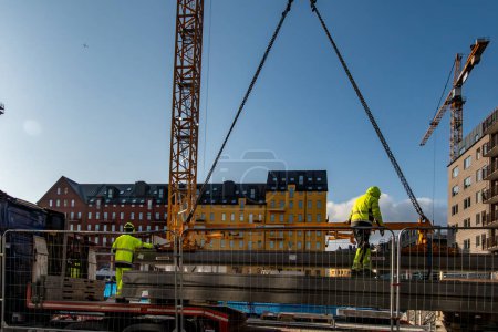Foto de Estocolmo, Suecia 4 de marzo de 2024 Los trabajadores manejan un gran bloque de cemento fundido desde un camión hasta una grúa en el distrito de Sodermalm. - Imagen libre de derechos