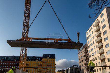 Foto de Estocolmo, Suecia 4 de marzo de 2024 Los trabajadores manejan un gran bloque de cemento fundido desde un camión hasta una grúa en el distrito de Sodermalm. - Imagen libre de derechos