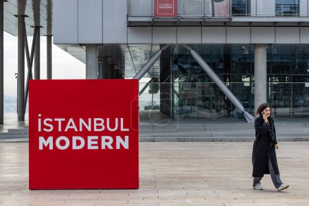 Téléchargez les photos : Istanbul, Turquie 19 mars 2024 Un panneau pour le Musée d'Art Moderne d'Istanbul dans le quartier Galataport et une femme piétonne. - en image libre de droit