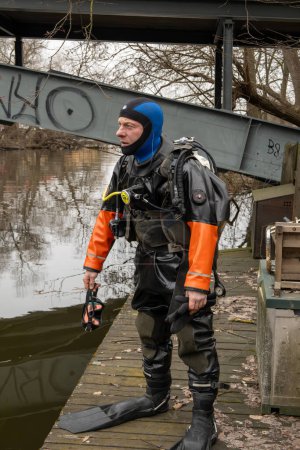 Téléchargez les photos : Stockhom, Suède 1 avril 2024 Un plongeur se prépare à entrer dans l'eau pour ramasser les ordures du fond du canal Palsundet au centre-ville de Stockholm. - en image libre de droit
