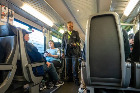 Photo for Vienna, Austria April 5, 2024 A conductor checks tickets  aboard the City Airport Train, or CAT - Royalty Free Image