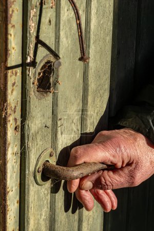 Téléchargez les photos : Stockholm, Suède Une main tend la main vers une poignée de porte dans une cabane en bois abandonnée et en ruine dans les bois. - en image libre de droit