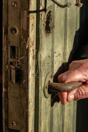 Téléchargez les photos : Stockholm, Suède Une main tend la main vers une poignée de porte dans une cabane en bois abandonnée et en ruine dans les bois. - en image libre de droit