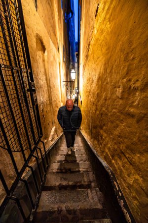 Stockholm, Sweden A man walks in the city's narrowest alley, Marten Trotzigs Grand in Gamla Stan or Old Town at night.