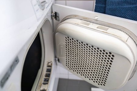 Un hombre quita pelusa de una secadora de ropa eléctrica