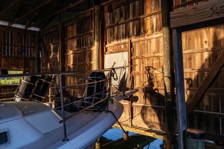 Foto de Solomons, Maryland Estados Unidos Un barco está amarrado dentro de una casa de botes de madera en la orilla del río Patuxent al amanecer. - Imagen libre de derechos