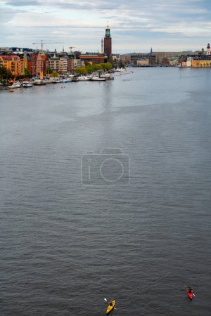 Photo for Stockholm, Sweden May 12, 2024 Kayakers in downtown Stockholm and the City Hall in the  Riddarjarden bay. - Royalty Free Image