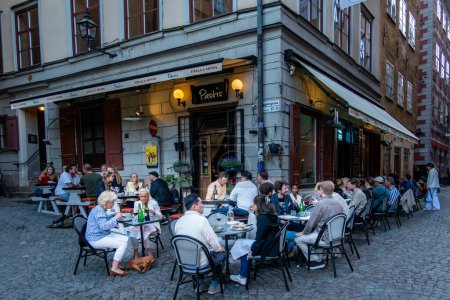 Foto de Estocolmo, Suecia 17 de mayo de 2024 Personas sentadas fuera del Pastis Bistro en Kopmangatan en el casco antiguo o Gamla Stan. - Imagen libre de derechos