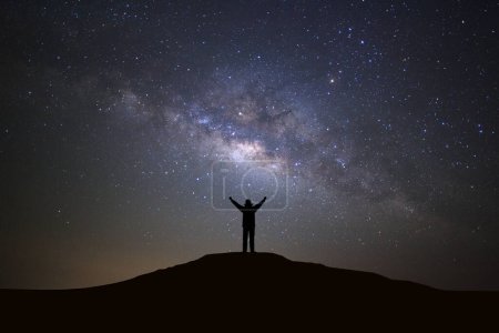 Téléchargez les photos : Paysage avec galaxie de la voie lactée, ciel étoilé nocturne avec étoiles et silhouette d'un sportif debout avec les bras levés sur la haute montagne
. - en image libre de droit