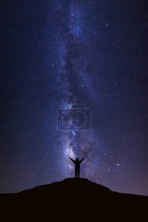Foto de Paisaje con Vía Láctea, Cielo nocturno con estrellas y silueta de hombre de pie sobre alta montaña - Imagen libre de derechos