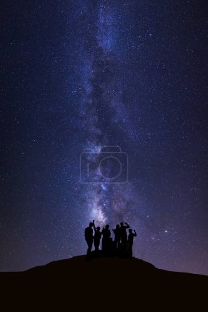 Téléchargez les photos : Paysage avec voie lactée, Ciel nocturne avec étoiles et silhouette de personnes heureuses debout sur une haute montagne - en image libre de droit
