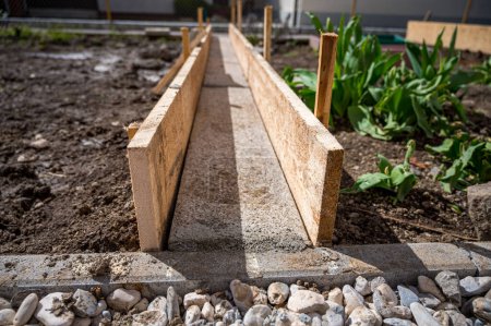 Téléchargez les photos : Construire un sentier en béton à travers le potager à l'aide de planches en bois. Projet de bricolage o améliorer le jardinage. - en image libre de droit