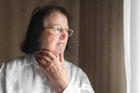 Foto de Retrato de una anciana sosteniendo su garganta - Imagen libre de derechos