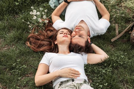 Photo for Top view of a young romantic couple lying in the grass - Royalty Free Image