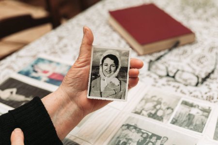 Photo for CIRCA 1970: Elderly woman hands holding vintage, black and white photo of the young woman. Passing of time concept - Royalty Free Image