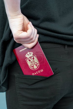 Téléchargez les photos : Femme sortant son passeport serbe de sa poche arrière - en image libre de droit