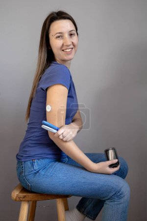 Girl sitting with sensor glucose patch on her arm