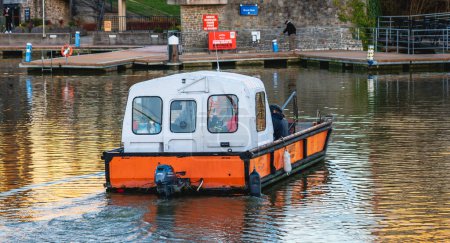 Téléchargez les photos : Bristol, Angleterre - 21 janvier 2023 : Petit bateau avec des gens traversant la voie navigable près de Brunel's SS Grande-Bretagne - en image libre de droit