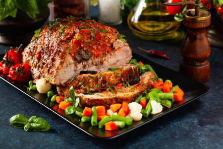 Photo for Whole roasted, stuffed with tomatoes and olives, pork neck. Dark background, dark mood. - Royalty Free Image