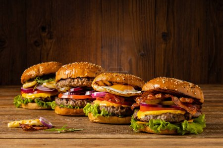 Rindfleisch-Geflügel-Burger mit Spiegelei, Speck und gegrilltem Halloumi-Käse. Holz, natürlicher Hintergrund. Dunkles Styling.