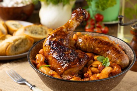 Traditional French one-pot dish with beans, chicken and white sausage. Cassoulet. Natural wooden background.